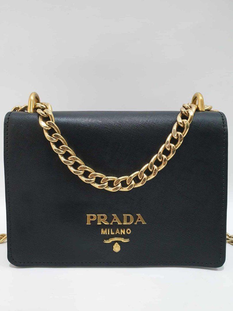 Prada Chain Crossbody Bag (Category: Luxury Bags & Wallets) located in Quezon City. Submitted by happy_shopperrr (Listing ID 1395101459, Image 1). Description: - Authentic Prada crossbody bag - Black leather exterior - Gold Prada logo - Gold chain strap - Flap closure - Contrasting blue and black color scheme - Compact and stylish design - Perfect for everyday or special occasions.