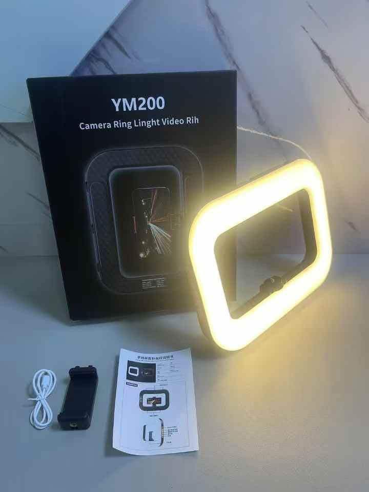 YM200 Handheld Rechargeable (8000mah)Ring Light (Category: Lighting & Studio Equipment) located in Manila. Submitted by iliasjen3082126 (Listing ID 1395130098, Image 2). Description: - YM200 Camera Ring Light for video recording - Includes: Ring light, phone holder, USB charging cable, user manual - Square-shaped ring light for bright illumination - Designed to hold your phone for easy recording - Box shows ring light with phone inside.