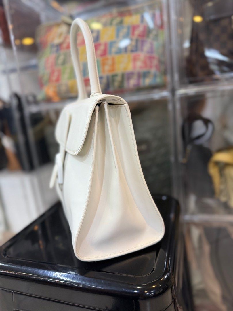 Delvaux White Leather Handbag (Category: Luxury Bags & Wallets) located in Manila. Submitted by fivethousandlilies (Listing ID 1395166878, Image 2). Description: - Delvaux white leather handbag - Structured design - Top handle - Distinctive buckle closure - Interior zippered pocket - Additional compartments ✅missing long strap ✅pm for more info - Delvaux logo on interior and buckle - Branded zipper pull.