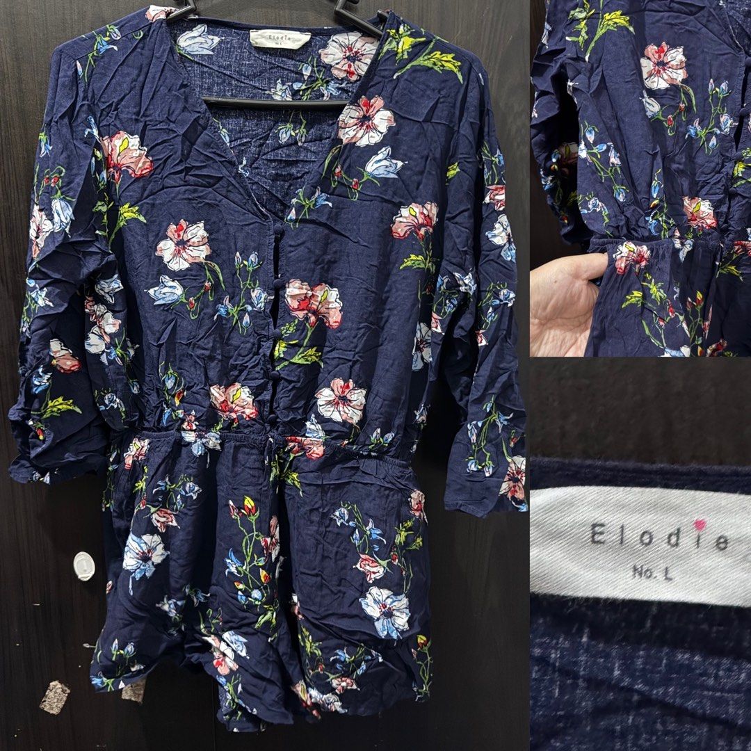(Get 3 for 350) Elodie Floral Romper (Category: Rompers) located in Taguig. Submitted by bnplswmakeup (Listing ID 1395189197, Image 1). Description: Navy blue floral romper from Elodie. Features a V-neckline, button-down front, and long sleeves. It has an elastic waist with a drawstring. The romper is adorned with a colorful floral print. Size M-L. MOP: BPI/Gcash Shipping via J&T/Grab/Lalamove.