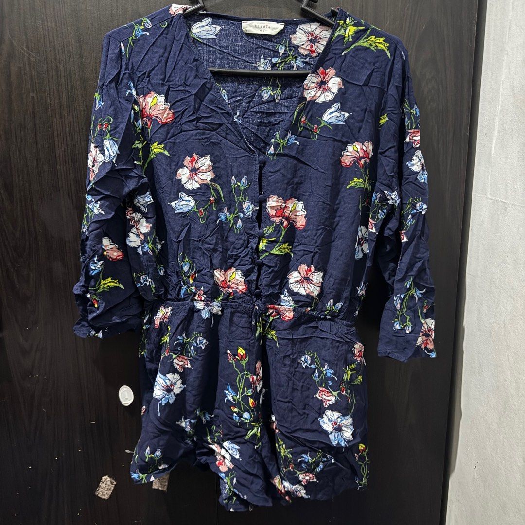 (Get 3 for 350) Elodie Floral Romper (Category: Rompers) located in Taguig. Submitted by bnplswmakeup (Listing ID 1395189197, Image 2). Description: Navy blue floral romper from Elodie. Features a V-neckline, button-down front, and long sleeves. It has an elastic waist with a drawstring. The romper is adorned with a colorful floral print. Size M-L. MOP: BPI/Gcash Shipping via J&T/Grab/Lalamove.