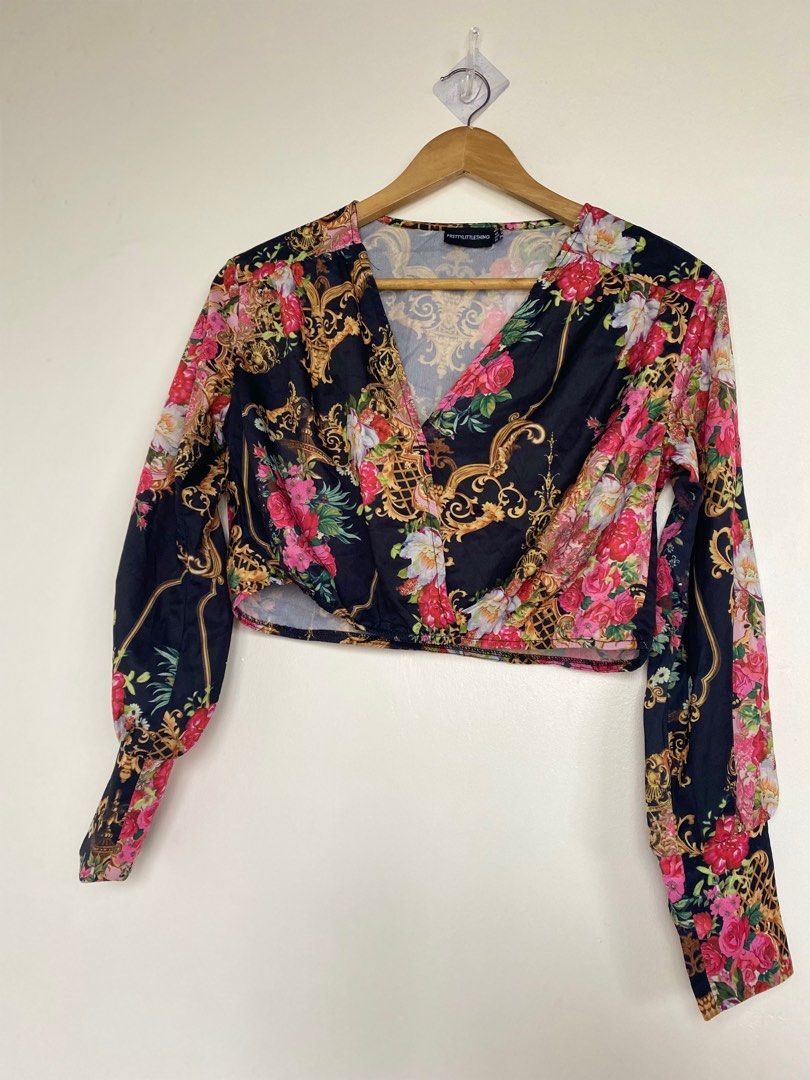 Black (Category: Blouses) located in Cavite. Submitted by jaydaascollection (Listing ID 1395253562, Image 2). Description: - PrettyLittleThing crop top - Features a flattering wrap style - Long sleeves and V-neckline - Eye-catching baroque and floral print - Colors: Black base with gold, pink, and red accents - Size Medium.