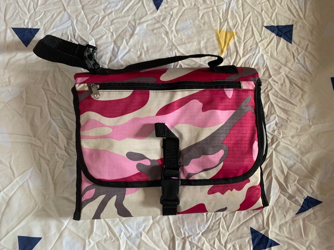 Baby’s PortableChanging Pad (Category: Changing Mats & Accessories) located in Paranaque City. Submitted by elainegrace22 (Listing ID 1395519253, Image 1). Description: - Stylish pink camouflage design - Unfolds to a padded changing surface - Includes a pocket and a mesh compartment for cleaning essentials - Features a zippered pocket - Comes with a strap for easy carrying - Folds up and secures with a buckle - Interior color: Light grey.