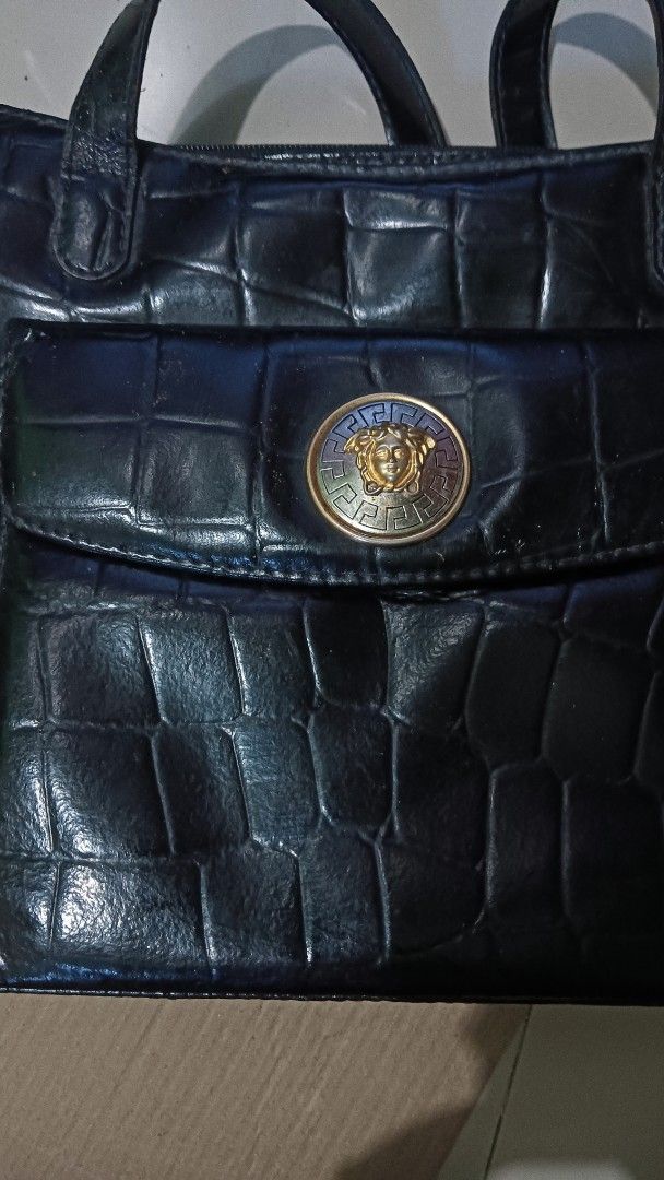 Gianni Versace Black Handbag (Category: Luxury Bags & Wallets) located in Laoag. Submitted by catrnzjb153008 (Listing ID 1395390459, Image 2). Description: - Gianni Versace handbag - Black color - Crocodile-like embossed exterior - Gold-tone Medusa head emblem on front pocket - Versace logo print interior lining - Zipper closure - Gold-tone zipper pull with Gianni Versace logo - Dual handles .