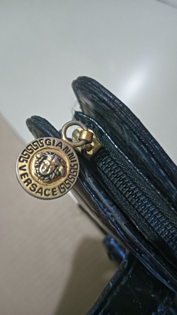 Gianni Versace Black Handbag (Category: Luxury Bags & Wallets) located in Laoag. Submitted by catrnzjb153008 (Listing ID 1395390459, Image 3). Description: - Gianni Versace handbag - Black color - Crocodile-like embossed exterior - Gold-tone Medusa head emblem on front pocket - Versace logo print interior lining - Zipper closure - Gold-tone zipper pull with Gianni Versace logo - Dual handles .