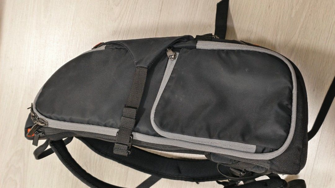 Manfrotto Camera Backpack (Category: Camera Bags & Carriers) located in Kuala Lumpur. Submitted by s.russianroulette (Listing ID 1395508017, Image 2). Description: Durable Manfrotto camera backpack with multiple compartments and adjustable straps. Features a padded back and shoulder straps for comfortable carrying. Includes side pockets and a top handle. The backpack has a sleek black design with grey accents and orange details. Perfect for photo