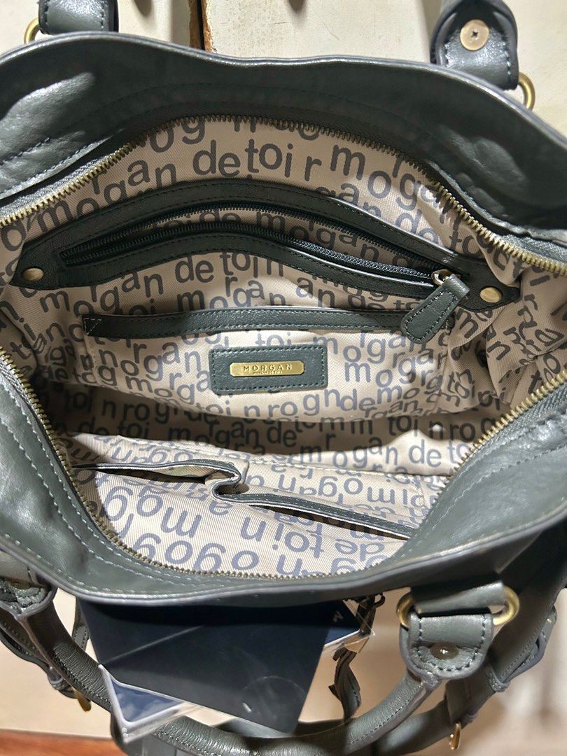 Morgan de Toi Handbag (Category: Luxury Bags & Wallets) located in Quezon City. Submitted by asiaco (Listing ID 1395437041, Image 2). Description: - Morgan de Toi handbag - Dark grey color - Top handle and detachable shoulder strap - Multiple compartments for organization - Interior lining with brand pattern - Gold-colored hardware and zipper closures.