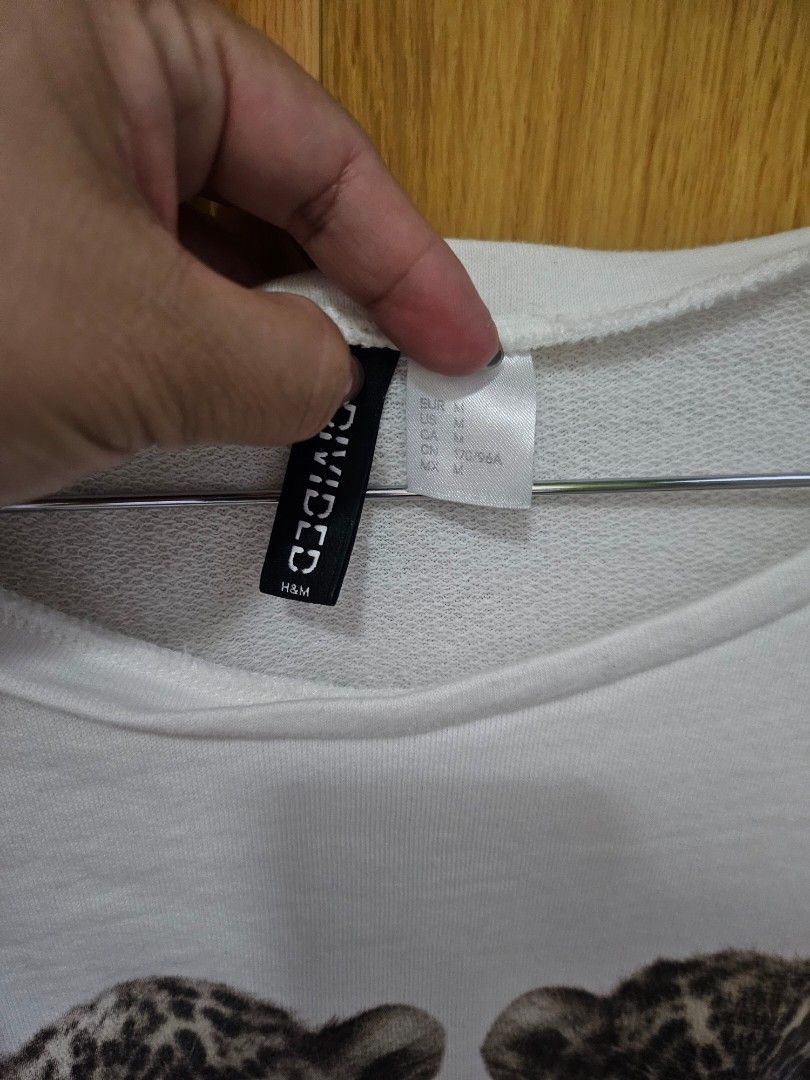 H&M Divided Feline Sweatshirt (Category: Longsleeves) located in Quezon City. Submitted by mlr19 (Listing ID 1395662863, Image 3). Description: - H&M Divided white sweatshirt - Features a 'Feline' print with two leopard cubs - Three-quarter sleeves - Round neckline - Simple, casual style - Perfect for everyday wear - Size tag visible in photos.