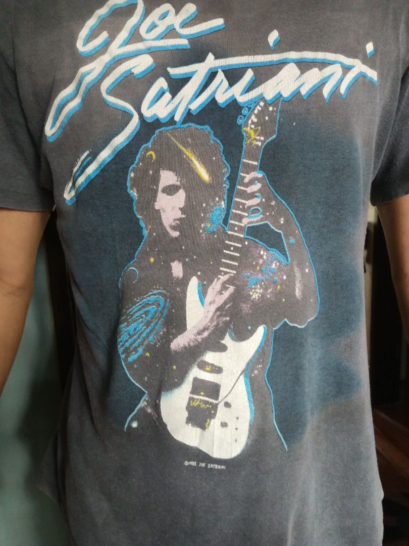 Joe Satriani Graphic Tee (Category: Tshirts & Polo Shirts ) located in Manila. Submitted by _fashionforward_ (Listing ID 1395582404, Image 1). Description: - Vintage Joe Satriani graphic tee - Features a graphic of Joe Satriani playing guitar - Copyright date: 1993 - Color: Dark grey - Style: Crew neck, short sleeves.