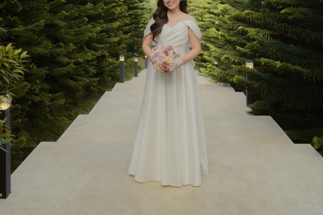 Wedding Gown Classic Mimimalist (Category: Evening dresses & gowns) located in Makati City. Submitted by stufflookup (Listing ID 1390617397, Image 2). Description: My wedding gown is finally up for RENT! I swear, I received countless compliments on this, kulang na lang i-try din nila 😂 Used last April 2025 Designer: Lauren Vito Original price was 50k+ Deposit: 20k Can be worn in 3 ways 🤗 This gown features: 1. detachable sleeves (hand-sown yung