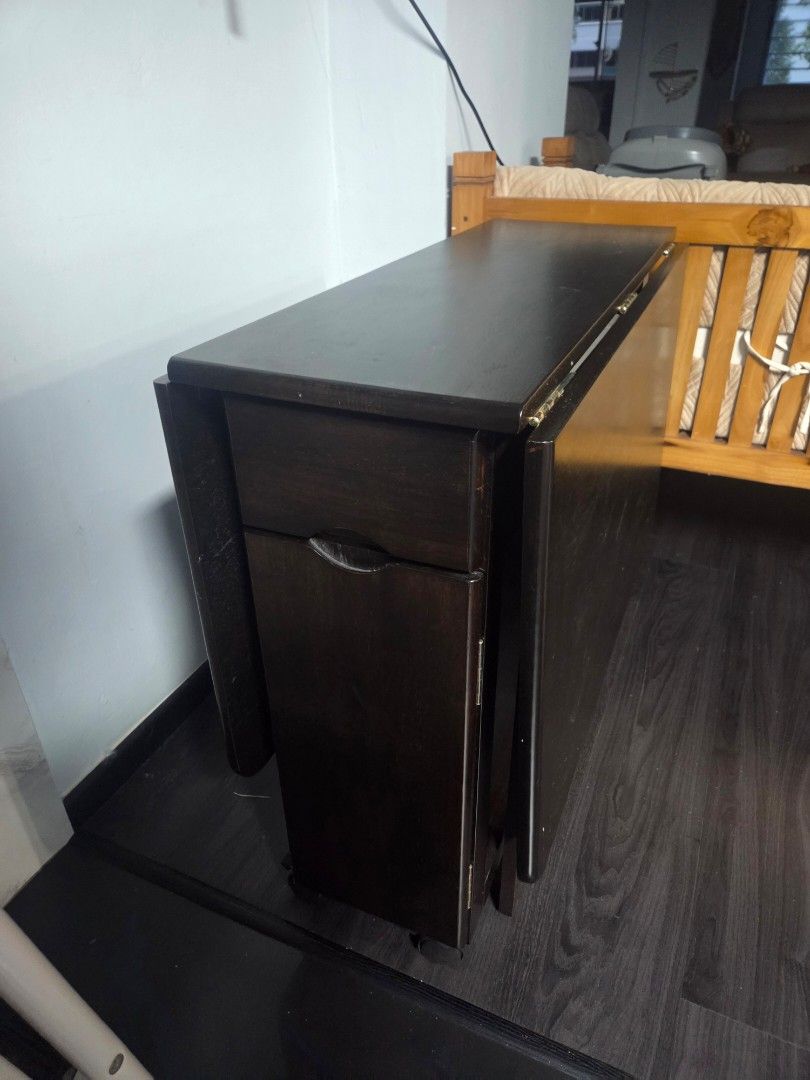 Breakfast Table (Category: Tables & Sets) located in Singapore. Submitted by Sha21_ (Listing ID 1391190846, Image 2). Description: - Dark wood cabinet - Although used, only used for keeping plastic bags. Good condition - Suitable for storage use - 1 drawer slide & 1 open door - No wear and tear present - Rarely used. -Foldable on both side -Original price 500$.
