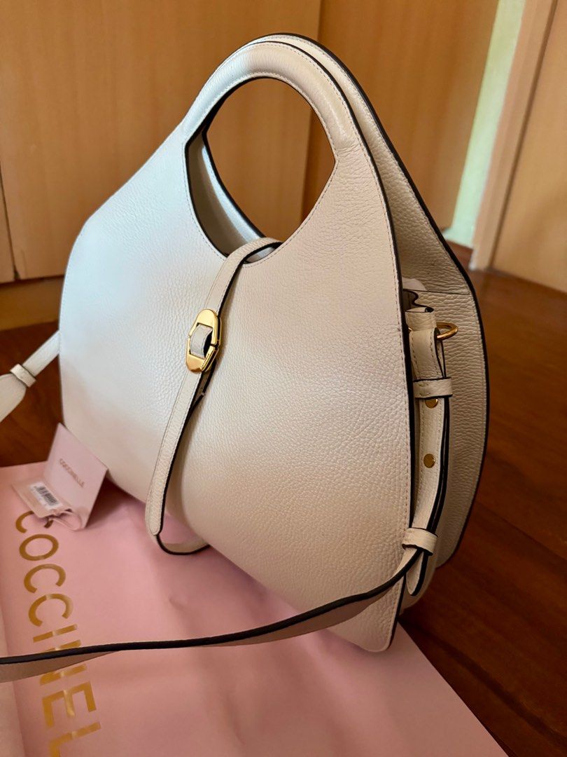 Hobo Bag (Category: Luxury Bags & Wallets) located in Rizal. Submitted by nixpreloved09 (Listing ID 1413033141, Image 3). Description: - Cream Coccinelle hobo bag - Unique crescent shape - Top handle and detachable shoulder strap - Gold-tone buckle detail - Includes matching coin purse - Comes with dust bag and tags - Versatile for everyday or special events.