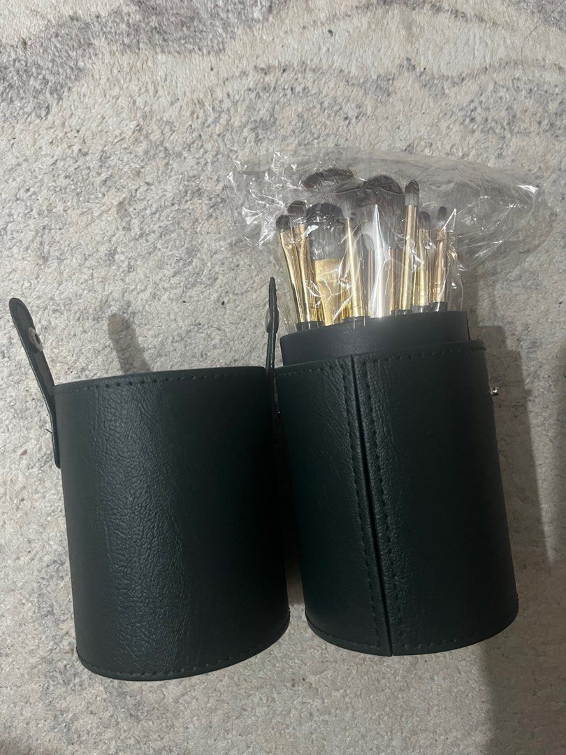 Makeup Brush Set with Leather Holder (Category: Makeup) located in Rizal. Submitted by cassappl (Listing ID 1412910166, Image 1). Description: - Makeup brush set - Includes a variety of brush types (12pcs total) - Comes with a dark green cylindrical case with a handle - Brushes feature gold and dark green handles.