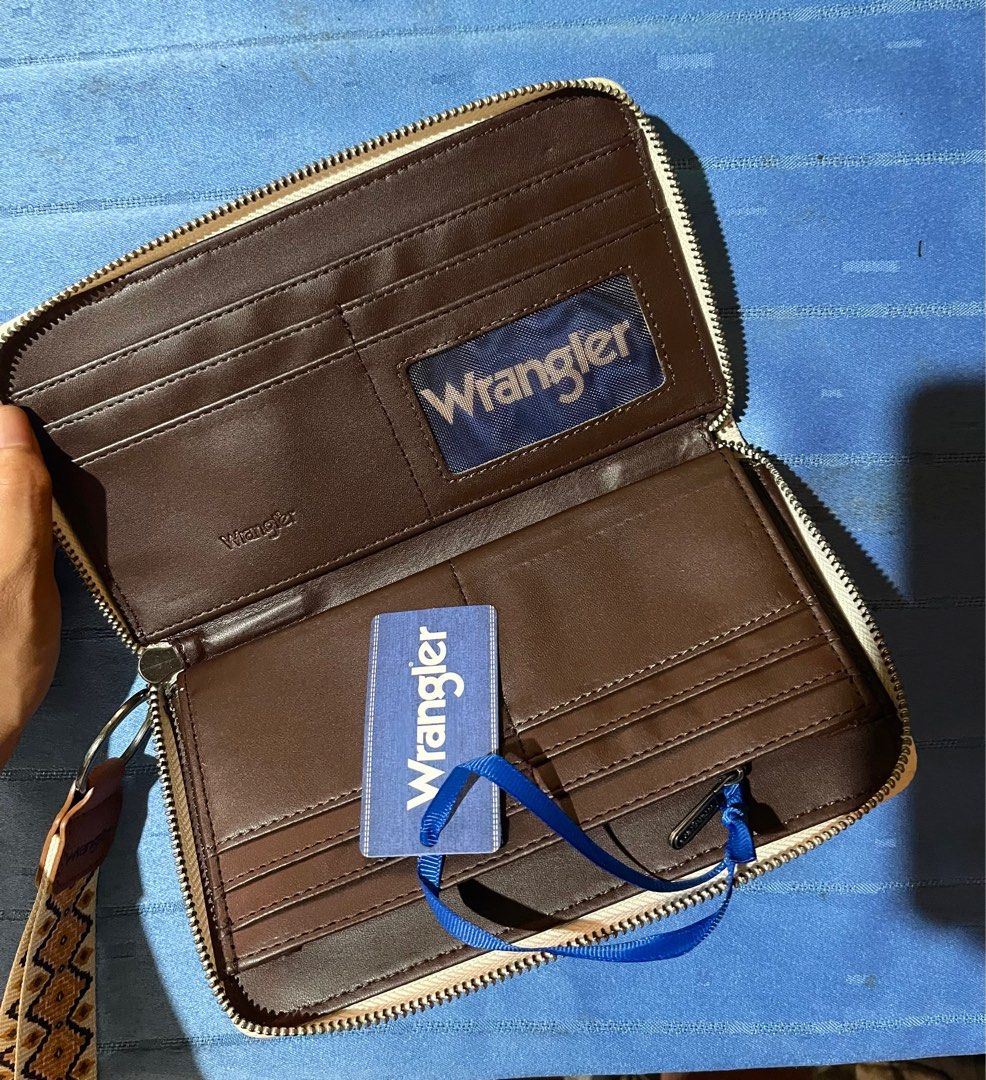 Wrangler Clutch Wallet (Category: Luxury Bags & Wallets) located in Bulacan. Submitted by marycristh50365 (Listing ID 1412898086, Image 3). Description: Decluttering NEW - Wrangler clutch wallet - Unique patterned design - Includes wrist strap - Multiple compartments - Zippered closure - Comes with brand tag - Includes original box - Interior: Solid brown - Exterior: Mixed colors and textures.
