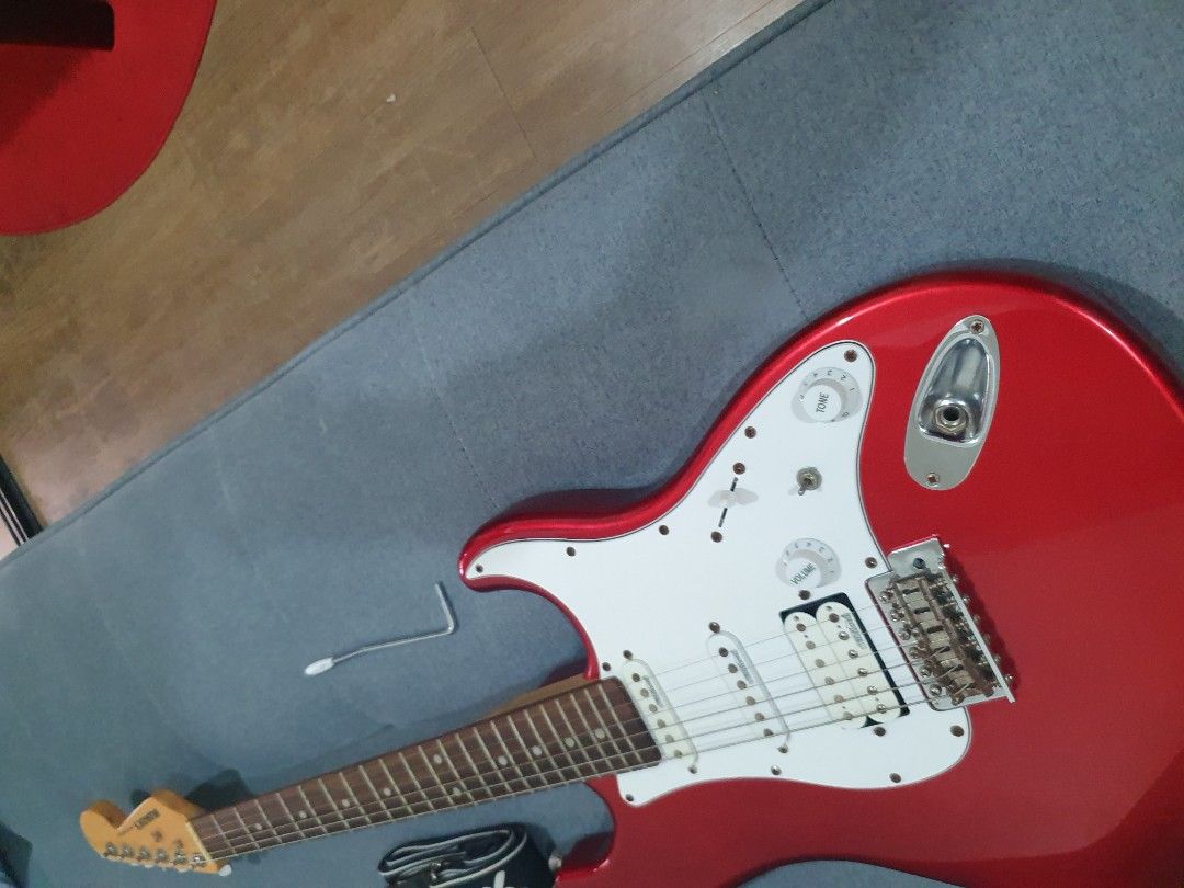 Busker's Red Electric Guitar (Category: Musical Instruments) located in Paranaque City. Submitted by ghanreagan15.1 (Listing ID 1414672371, Image 2). Description: - Red Busker's electric guitar - White pickguard - Three pickups - Glossy red finish - Includes strap and wrench - Busker's logo on headstock - 6 strings note slightly rust hardware but Good condition and action comes with tremolo guitar strap and free guitar stand - Tuning pegs.