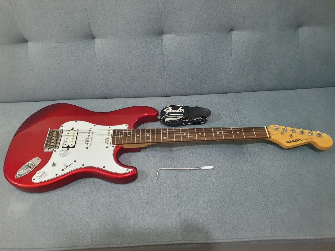 Busker's Red Electric Guitar (Category: Musical Instruments) located in Paranaque City. Submitted by ghanreagan15.1 (Listing ID 1414672371, Image 1). Description: - Red Busker's electric guitar - White pickguard - Three pickups - Glossy red finish - Includes strap and wrench - Busker's logo on headstock - 6 strings note slightly rust hardware but Good condition and action comes with tremolo guitar strap and free guitar stand - Tuning pegs.