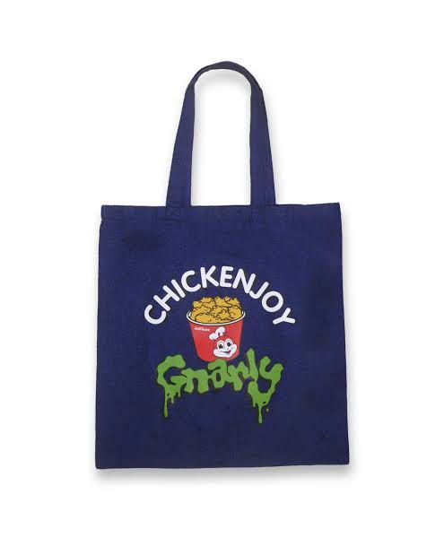 Jollibee x KATSEYE Tote Bag (Category: Tote Bags) located in Taguig. Submitted by sourcedbym (Listing ID 1414671848, Image 2). Description: Tote bag is a collaboration between Jollibee and KATSEYE. It features the "Chickenjoy Gnarly" design on one side and the Jollibee x KATSEYE logo on the other. The bag is navy blue and has two handles for carrying..