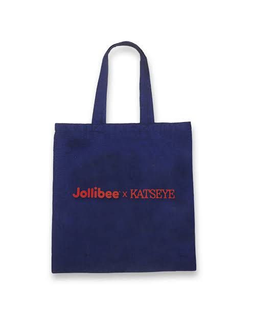 Jollibee x KATSEYE Tote Bag (Category: Tote Bags) located in Taguig. Submitted by sourcedbym (Listing ID 1414671848, Image 3). Description: Tote bag is a collaboration between Jollibee and KATSEYE. It features the "Chickenjoy Gnarly" design on one side and the Jollibee x KATSEYE logo on the other. The bag is navy blue and has two handles for carrying..