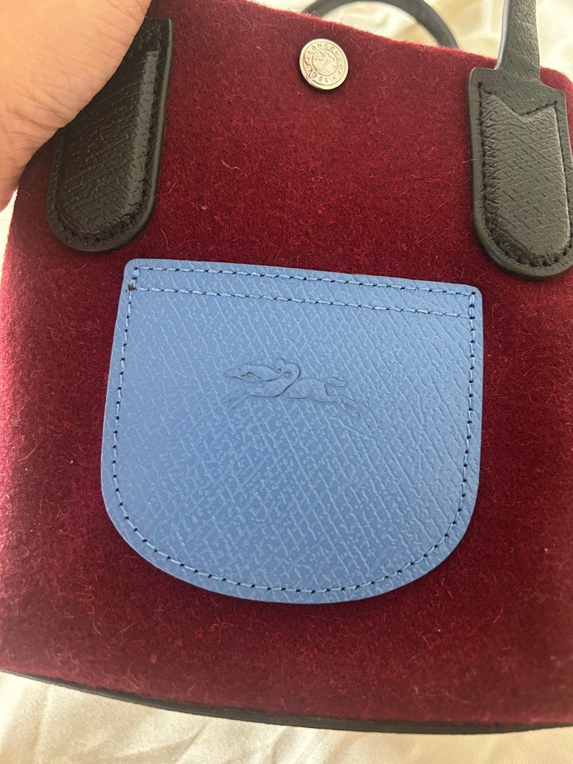 Longchamp Le Pliage Cuir Tote Bag (Category: Luxury Bags & Wallets) located in Cabanatuan. Submitted by krnlim (Listing ID 1414627531, Image 2). Description: Authentic Longchamp Le Pliage Cuir tote bag. Features a burgundy felt body with a blue front pocket and black leather handles. Includes a snap closure and a Longchamp logo on the front pocket and the button. Made in France. The tag shows the model number 10172HBL009..