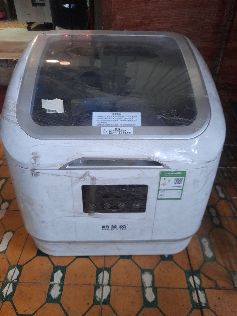 OLEVIN Dishwasher (Category: Dishwasher) located in Valenzuela. Submitted by newbear.425b6e (Listing ID 1414717295, Image 1). Description: - Includes user manual - Comes with a pack of dishwashing tablets - Features a clear door - Control panel with multiple buttons - Dish rack inside for organized washing - Includes a hose - Stylish white exterior with silver trim.