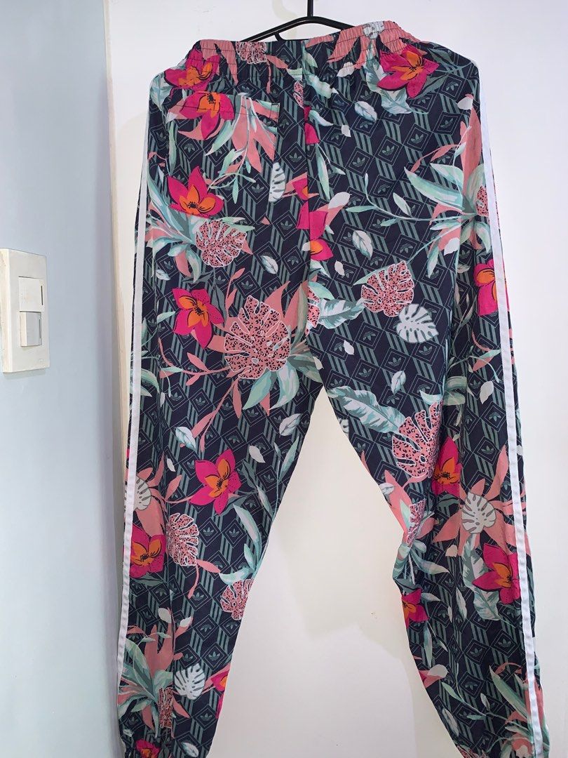 Adidas Floral Print Track Pants (Category: Other Bottoms) located in Taguig. Submitted by seekstyleph (Listing ID 1414900441, Image 2). Description: - Hips 21”, Length 38” - Adidas track pants - Vibrant floral print - Iconic three stripes - Elastic waistband - Relaxed fit - Size: S (fits until Medium) - Made in Cambodia.