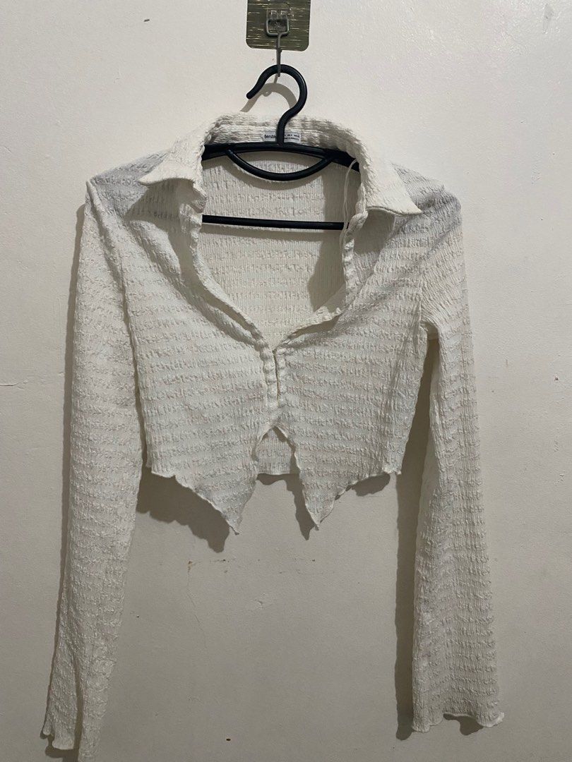 Bershka White Cropped Ratchet Top (Category: Sleeveless) located in Taguig. Submitted by yvezntually (Listing ID 1415034720, Image 1). Description: - Bershka cropped top - Color: White - Size: S but can fit upto med - Features: Collared neckline, long sleeves, button-up front - Fabric: Textured, crinkled - Used once.
