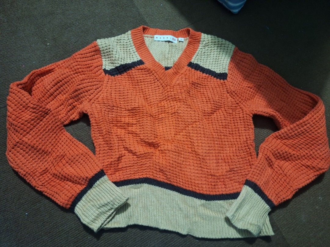 Marni x Uniqlo V-Neck Sweater (Category: Coats, Jackets and Outerwear) located in Cavite. Submitted by lilltevg (Listing ID 1414949369, Image 2). Description: - Marni x Uniqlo collaboration sweater. - Unique color block design. - V-neck style. - Long sleeves with ribbed cuffs. - Textured knit pattern. - Color scheme: Orange, beige, and navy blue. - Size tag is visible in the image..
