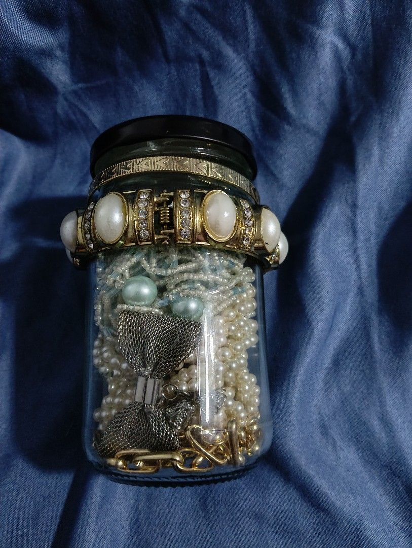 Mystery Jewelry Jar (Category: Accessory Holder, Box & Organizers) located in Iloilo. Submitted by katryce (Listing ID 1414950703, Image 3). Description: Collection of various jewelry pieces stored in a glass jar. Includes bracelets, necklaces, and beads in different colors and styles. Some pieces appear to be made of wood, pearls, and metal. The jar has a black lid and is displayed on a blue fabric background. .