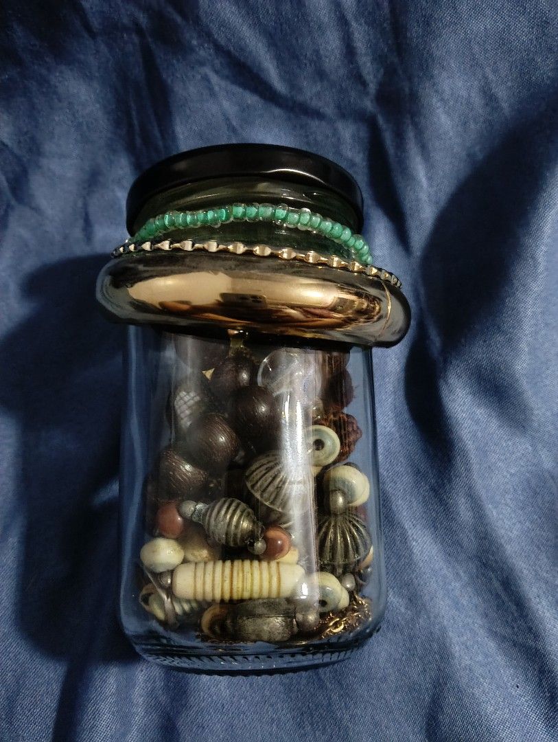 Mystery Jewelry Jar (Category: Accessory Holder, Box & Organizers) located in Iloilo. Submitted by katryce (Listing ID 1414950703, Image 1). Description: Collection of various jewelry pieces stored in a glass jar. Includes bracelets, necklaces, and beads in different colors and styles. Some pieces appear to be made of wood, pearls, and metal. The jar has a black lid and is displayed on a blue fabric background. .