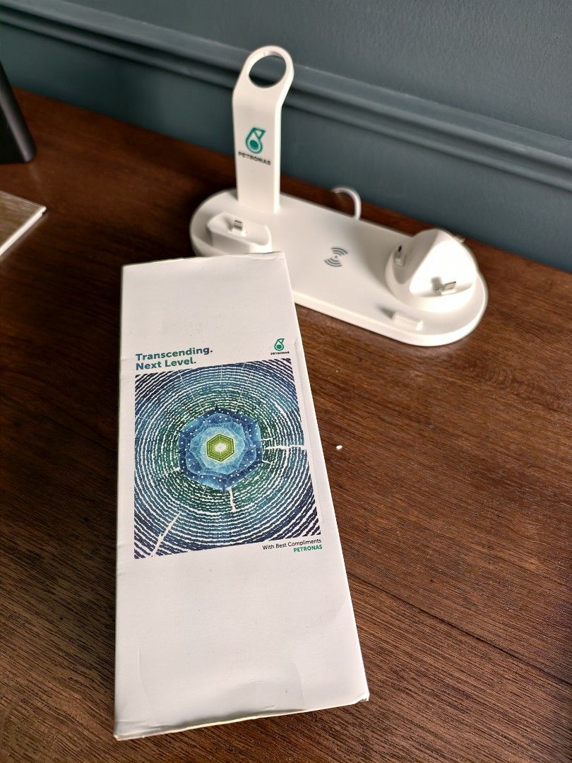 Petronas Multi-Function Charging Stand (Category: Other Gadgets) located in Petaling Jaya. Submitted by junkforfunk (Listing ID 1414844568, Image 3). Description: Petronas Multi-function charging stand is designed for iPhone, AirPods, and Apple Watch. It features a 4-in-1 rotatable charger dock with a USB phone/Type-C phone port. The stand has a wireless charging pad and a sleek white design with the Petronas logo. It comes with its original pack