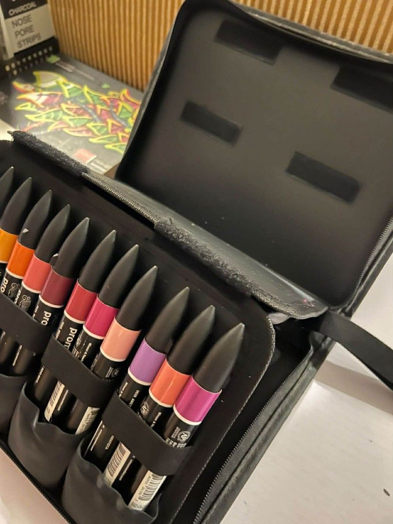 Winsor & Newton Promarker 24+1 Set (Category: Craft Supplies & Tools) located in Makati City. Submitted by msverify (Listing ID 1415026865, Image 3). Description: Winsor & Newton Promarker set with 24 markers and a blender. The set comes in a black case. The box shows the color range and the markers are dual-tipped. The set includes a variety of colors, including yellow, orange, red, pink, purple, blue, and green. The markers are student designer