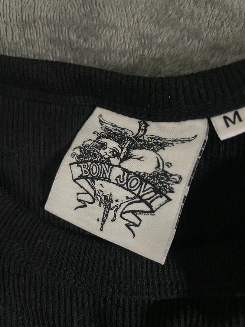 Bon Jovi Tank Top - Black (Category: Sleeveless) located in Rizal. Submitted by declutterwsky (Listing ID 1415219510, Image 2). Description: - Bon Jovi tank top - Features the Bon Jovi logo with a heart and wings design - Text: "BON JOVI" and "NEW JERSEY" - Size: M - Ribbed texture - Brand logo visible on inner tag.