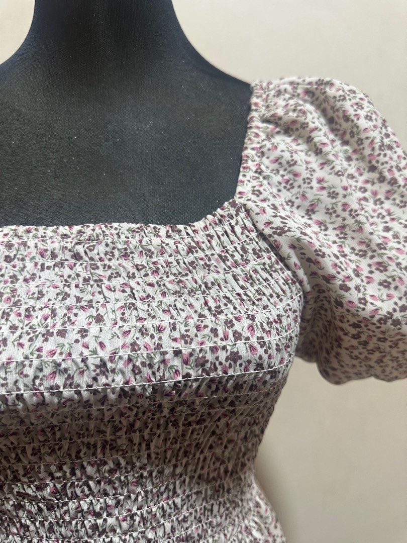 Floral Square Neck Top (Category: Blouses) located in Taguig. Submitted by sassythrifter (Listing ID 1415146222, Image 2). Description: Top features a square neckline and short puff sleeves. It has a fitted bodice with a smocked design and a peplum hem. The fabric is white with a delicate floral print in shades of purple and green. It is a stylish piece suitable for various occasions..