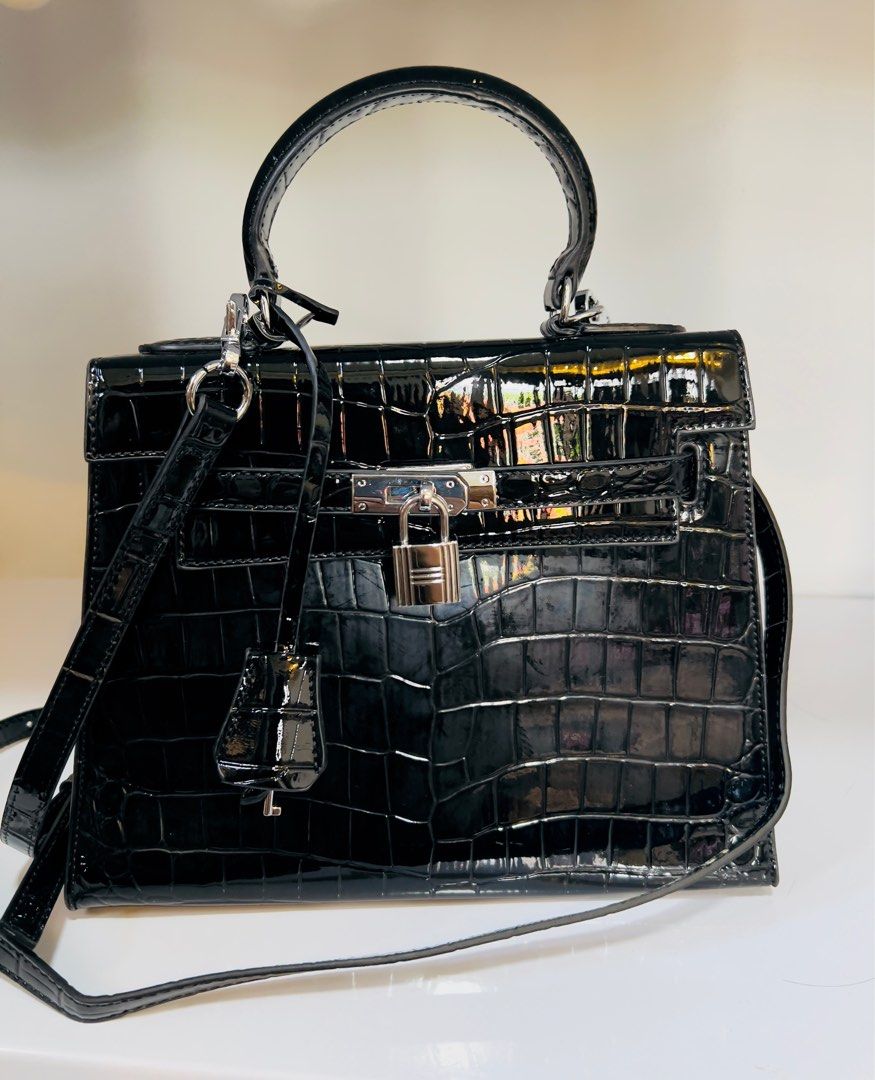 Black Crocodile-Embossed Handbag with Top Handle (Category: Luxury Bags & Wallets) located in Candelaria. Submitted by sac_du_jour (Listing ID 1415320145, Image 2). Description: - Black handbag with crocodile-embossed finish - Top handle and detachable shoulder strap - Silver-tone lock closure and hardware - Structured shape - Glossy material - Includes a small charm.