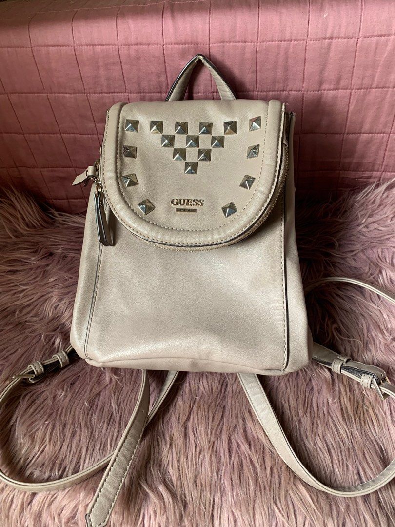 Guess Studded Backpack (Category: Backpacks) located in Cebu City. Submitted by declutter_ysh (Listing ID 1415243575, Image 2). Description: - Guess backpack in a neutral beige color. - has a flap closure with studded accents and a gold Guess logo. - has adjustable straps and multiple zippered compartments for storage..