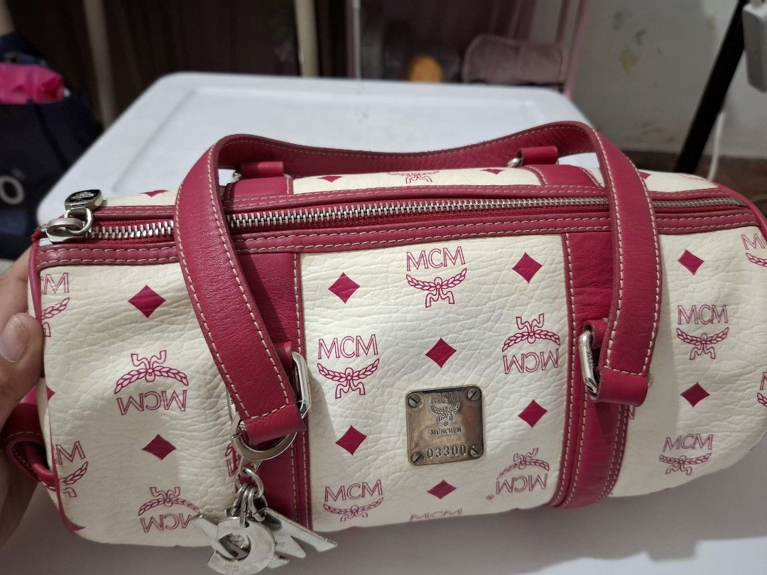 MCM Boston Bag (Category: Luxury Bags & Wallets) located in Antipolo. Submitted by prinsesa_dianne (Listing ID 1415428185, Image 1). Description: - Cream-colored body with MCM logo print - Pink leather accents - Top zipper closure - Dual top handles - Detachable charm - Interior zippered pocket - Metal logo plate on front.