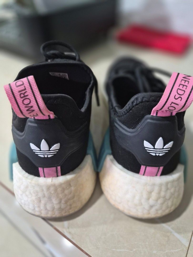 Adidas NMD_R1 'Needs Love' Sneakers (Category: Sneakers) located in Cavite. Submitted by bdzblls (Listing ID 1415527052, Image 3). Description: Adidas NMD_R1 sneakers in black with pink and blue accents. Features "Young Union" text on the side and "Needs Love" and "The World" on the heel tabs. Includes a unique lace charm. The insole has a colorful design with Adidas branding. Made in Vietnam, size US 6.5, UK 6, FR 39 1/3, JP 245, CHN 240. Bought