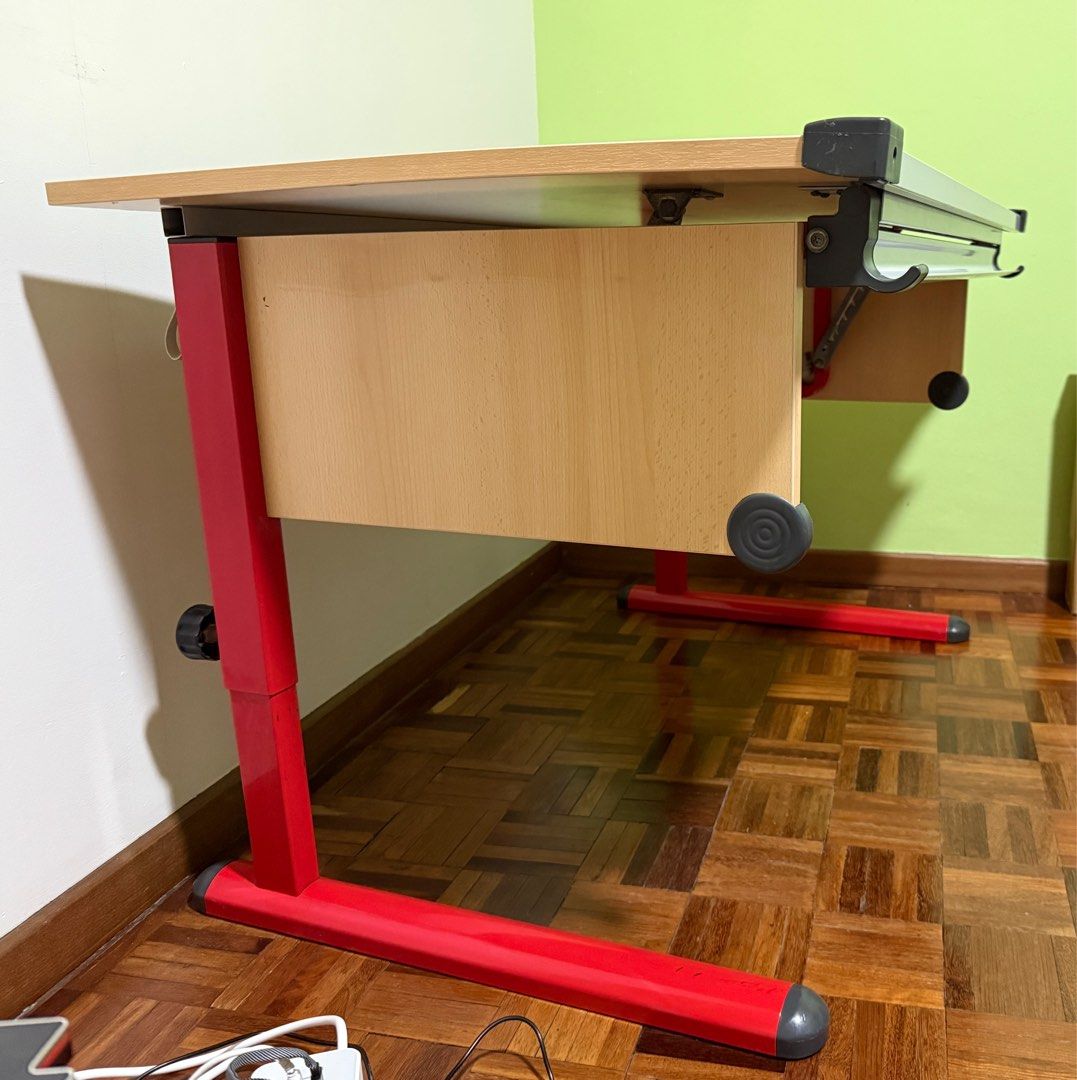 Adjustable Drafting Table - Red Frame (Category: Tables & Sets) located in Singapore. Submitted by cupcakeangel01 (Listing ID 1415548952, Image 2). Description: Good conditions Study /working table. 120 x 70 cm wood laminated table top, adjustable, tilting at your desired working angle up to 45deg. Adjustable height legs, min 70cm ht. Designed with a storage tray under the table. suitable for Art craft drawing / engineering drafting or used as co