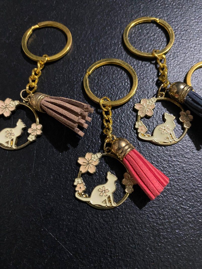 Cat and Flower Keychains with Tassels (Category: Charms) located in Valenzuela. Submitted by emg.everythingmustgo (Listing ID 1415554434, Image 3). Description: 100 each - Cat silhouette design with flower accents - Gold-colored ring, chain, and charm - Tassels available in brown, red, blue, green, and purple - Adds charm to keys or bags - Great gift for cat lovers.