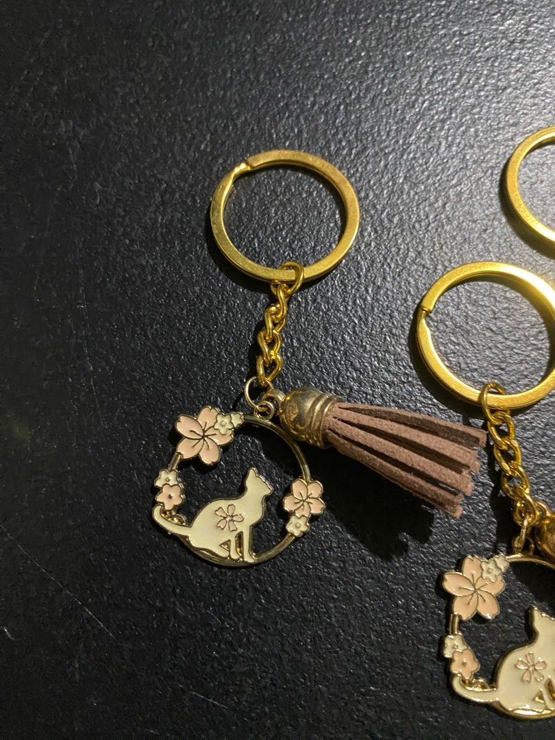 Cat and Flower Keychains with Tassels (Category: Charms) located in Valenzuela. Submitted by emg.everythingmustgo (Listing ID 1415554434, Image 2). Description: 100 each - Cat silhouette design with flower accents - Gold-colored ring, chain, and charm - Tassels available in brown, red, blue, green, and purple - Adds charm to keys or bags - Great gift for cat lovers.