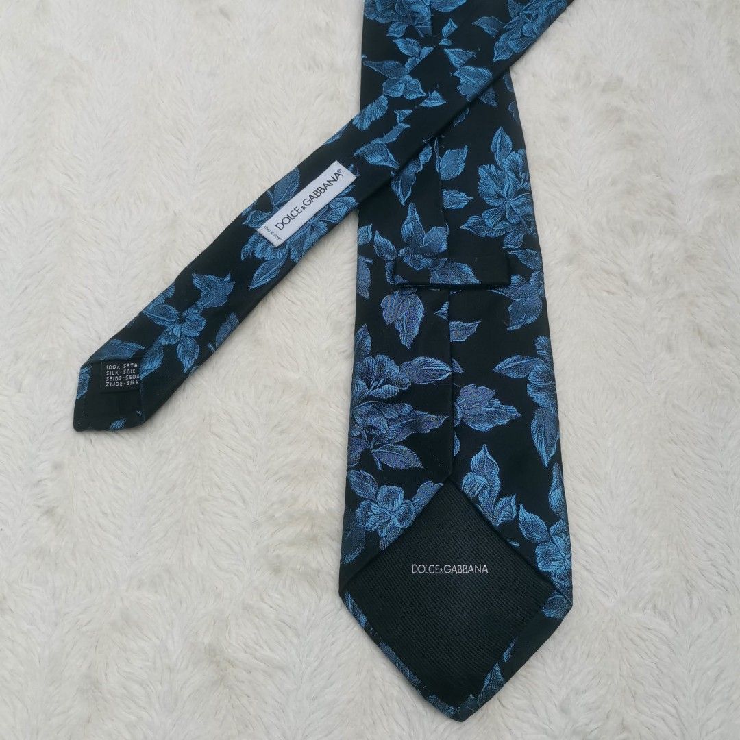 Dolce & Gabbana Floral Tie (Category: Ties) located in Manila. Submitted by titojay (Listing ID 1415456987, Image 1). Description: - Dolce & Gabbana tie - Silk material - Black background with blue floral design - Dolce & Gabbana logo present - Ideal for formal occasions.