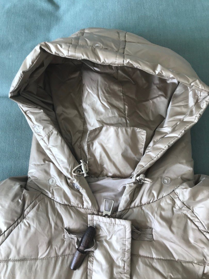 Down jacket (Category: Coats, Jackets and Outerwear) located in Singapore. Submitted by mtyzxhc_802 (Listing ID 1415456313, Image 3). Description: - Longline puffer jacket - Beige color - Features a hood and toggle closures - Lightly used, no visible wear - Versatile for various outfits - Perfect for staying warm and stylish.
