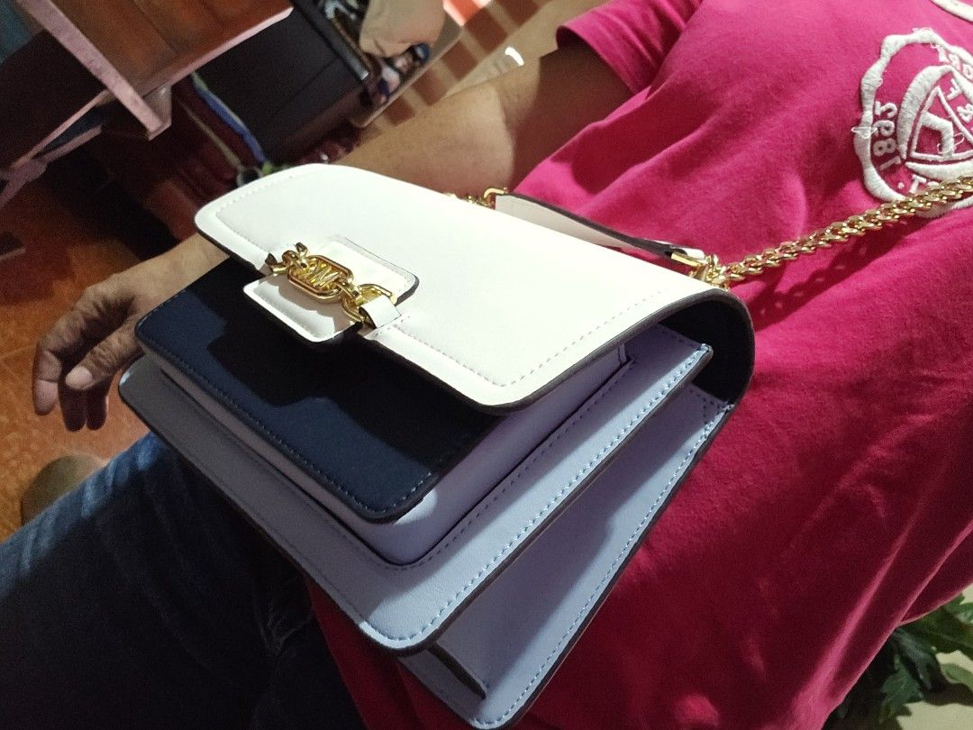 Michael Kors White Chain Shoulder Bag (Category: Luxury Bags & Wallets) located in Cavite. Submitted by thalitz40 (Listing ID 1413760793, Image 3). Description: - Brand new Michael Kors shoulder bag - Elegant white design - Features a stylish gold chain and clasp with the Michael Kors logo - Includes a detachable strap for versatile wear - Adorned with a charming flower-shaped keychain - Comes with the original box.