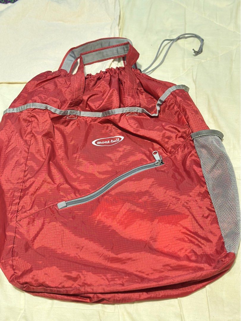 Mont-Bell Tote bag Pocketable Light (Category: Backpacks) located in General Santos City (Dadiangas). Submitted by toysville888 (Listing ID 1415490003, Image 2). Description: This is a red Mont-bell packable tote bag made from water-resistant nylon material. It features: An ultra-lightweight design that folds into a compact size. A spacious main compartment with drawstring closure. mesh side pocket for water bottles or other items. A front zipper