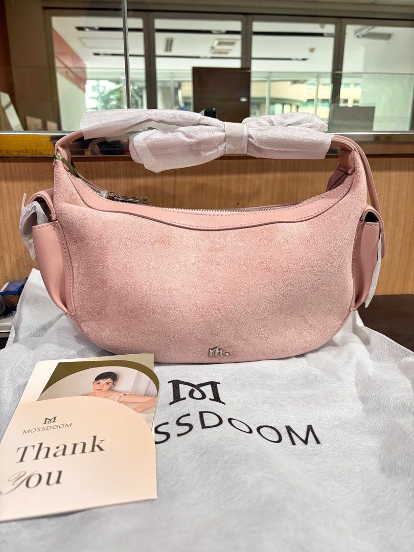 Mossdoom Pink Suede Hobo Bag (Category: Shoulder Bags) located in Paranaque City. Submitted by jessamm (Listing ID 1415625537, Image 1). Description: - Mossdoom hobo bag - Soft pink suede exterior - Curved design - Top handle - Side pockets - Includes dust bag - Silver zipper - Mossdoom logo visible.
