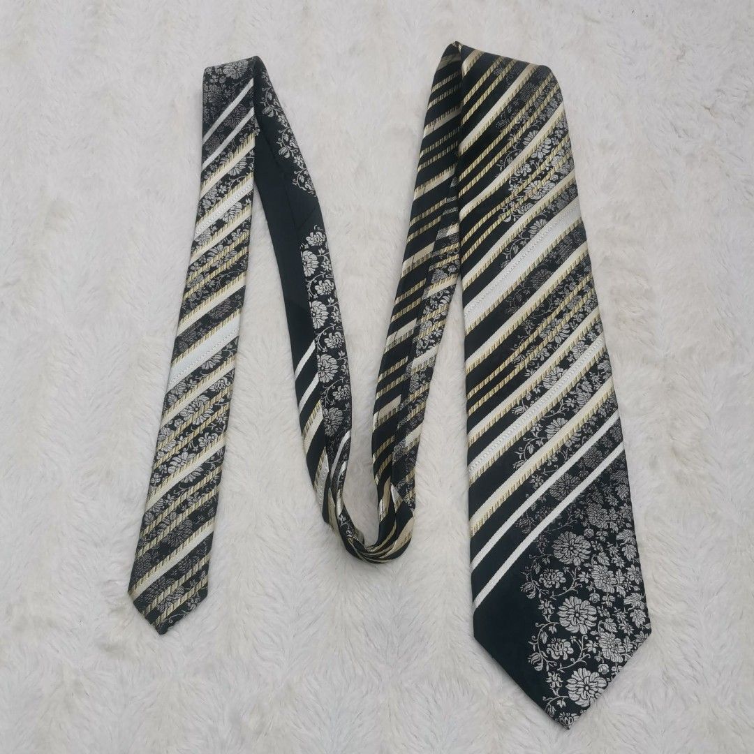 Nina Ricci Silk Tie (Category: Ties) located in Manila. Submitted by titojay (Listing ID 1415456560, Image 3). Description: Elegant Nina Ricci tie featuring a striking combination of black, white, and gold stripes with floral accents. The tie has a classic design with a standard width. The label is visible, confirming the brand. Perfect for adding a touch of sophistication to any outfit..