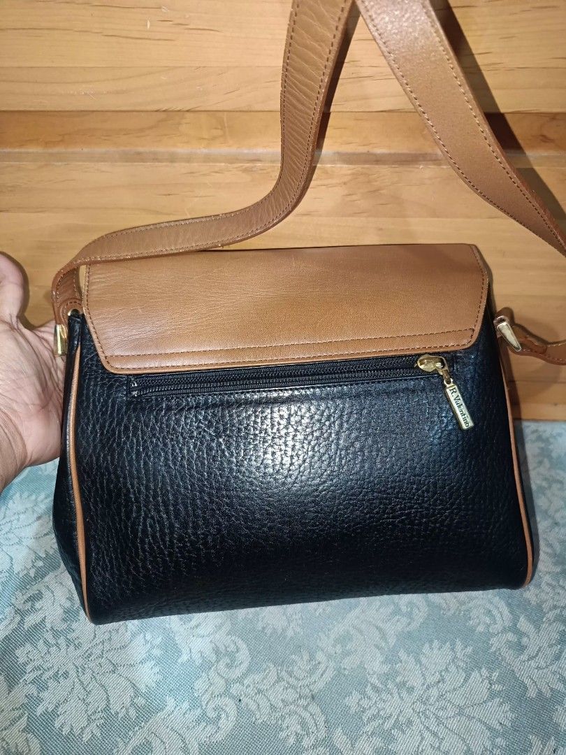 Rudolph Valentino Sling Bag (Category: Luxury Bags & Wallets) located in Baguio. Submitted by iyaberong48242 (Listing ID 1415434418, Image 2). Description: - Rudolph Valentino Shoulder Bag - Two-tone design: Brown flap, Black body - Gold-tone clasp - Adjustable long strap - Multiple interior compartments - Includes a zippered pocket - Authentic Ralph Valentino branding on clasp and inside -Meduim Size..