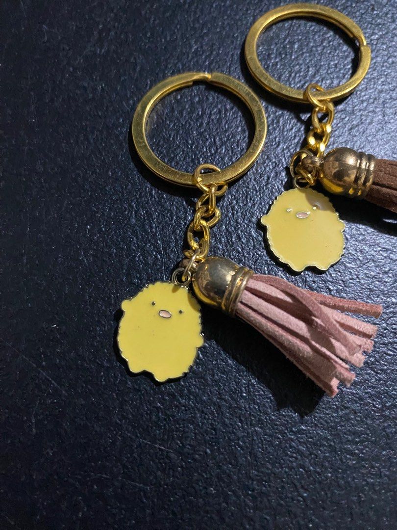 Sumikko Gurashi Keychain with Tassel (Category: Character Goods) located in Valenzuela. Submitted by emg.everythingmustgo (Listing ID 1415557991, Image 2). Description: 70 each Adorable Sumikko Gurashi keychains featuring a cute yellow character charm and a matching tassel. Each keychain has a gold-colored ring and chain. Available in various tassel colors: brown, purple, black, and pink. Perfect for adding a touch of charm to your keys, bags, or
