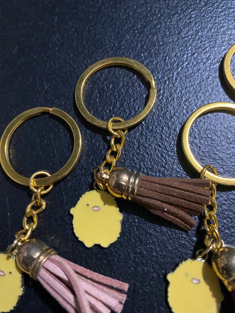 Sumikko Gurashi Keychain with Tassel (Category: Character Goods) located in Valenzuela. Submitted by emg.everythingmustgo (Listing ID 1415557991, Image 3). Description: 70 each Adorable Sumikko Gurashi keychains featuring a cute yellow character charm and a matching tassel. Each keychain has a gold-colored ring and chain. Available in various tassel colors: brown, purple, black, and pink. Perfect for adding a touch of charm to your keys, bags, or