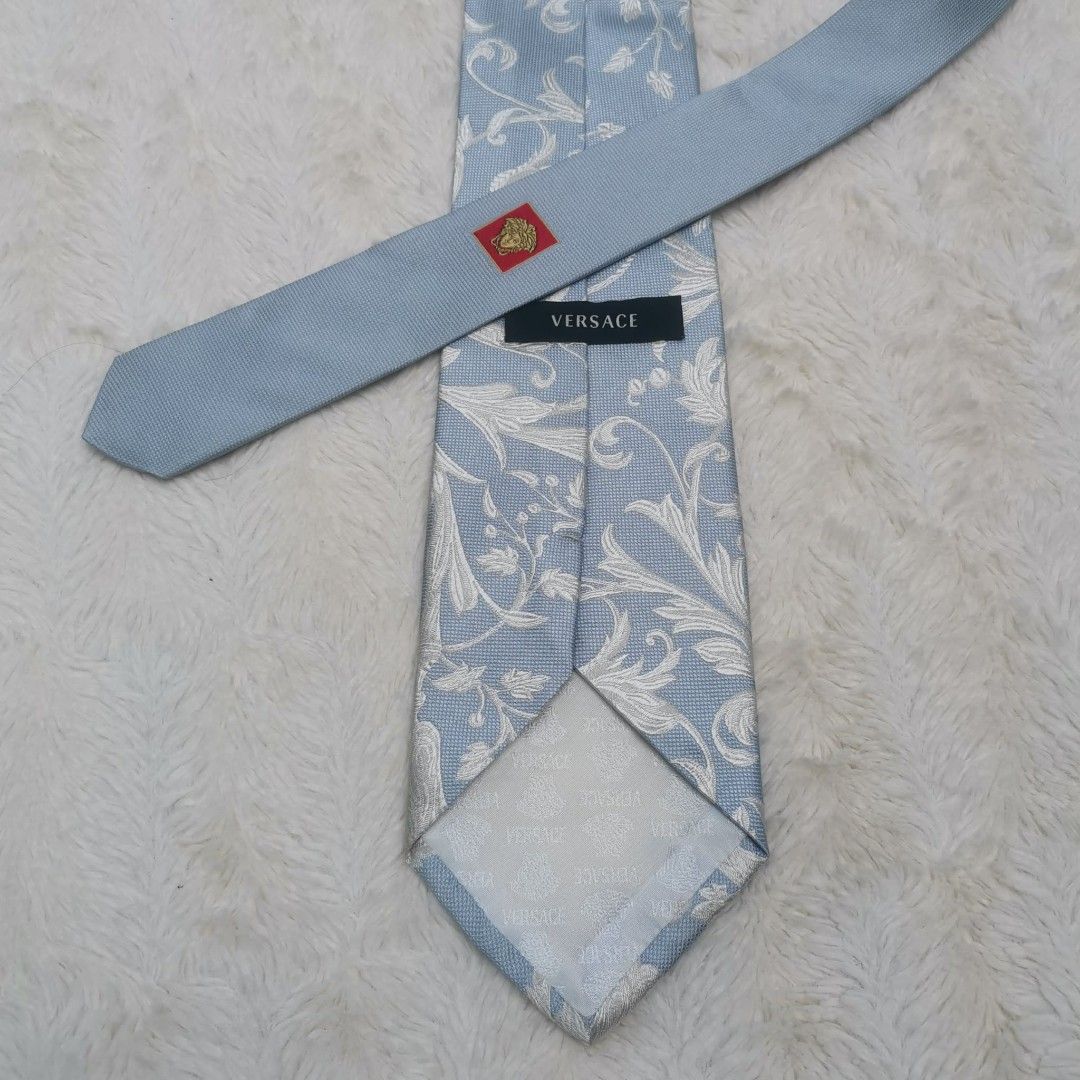 Versace Silk Tie (Category: Ties) located in Manila. Submitted by titojay (Listing ID 1415455452, Image 1). Description: - Versace silk tie - Light blue and white floral pattern - Classic design - Pointed end - Versace logo visible - Perfect for formal occasions.